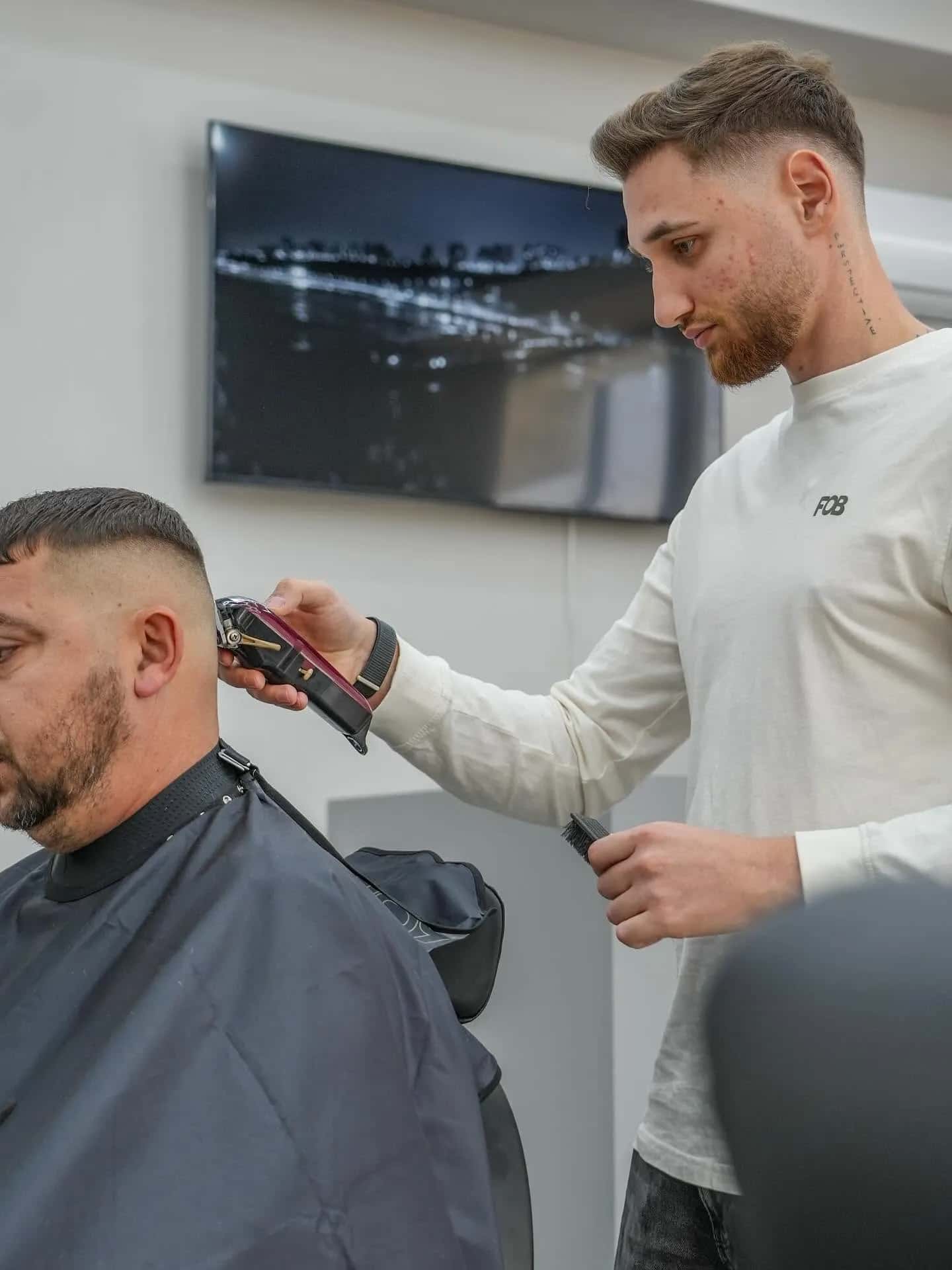Frizer făcând un fade cu mașina la R|B Barbershop