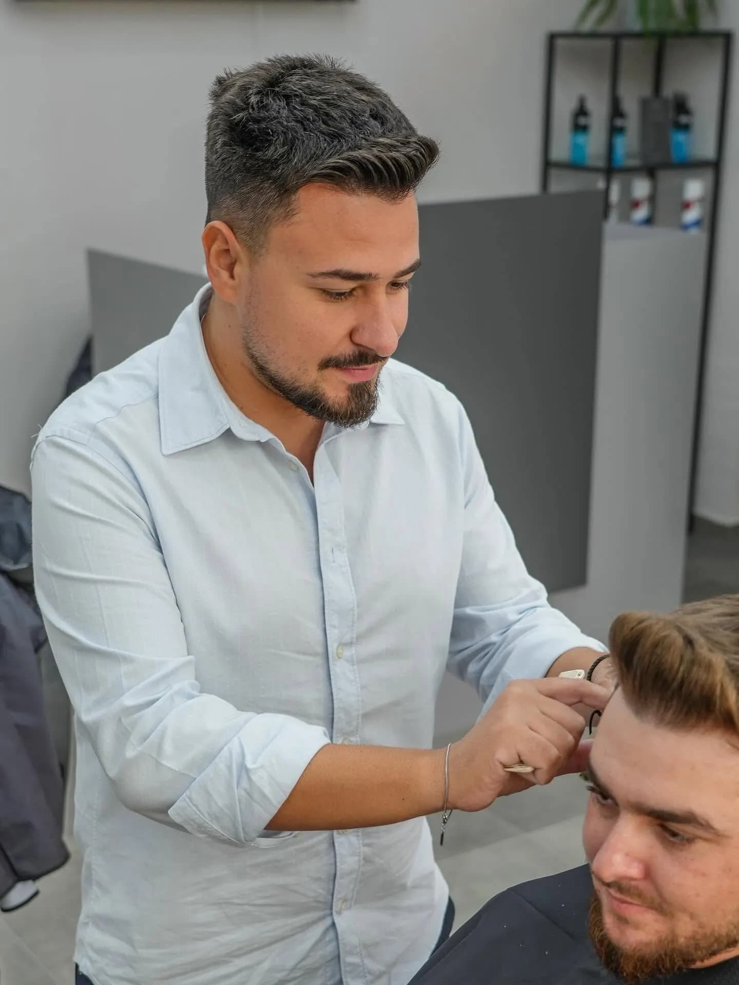 Frizer aranjând tunsoarea cu foarfeca la R|B Barbershop