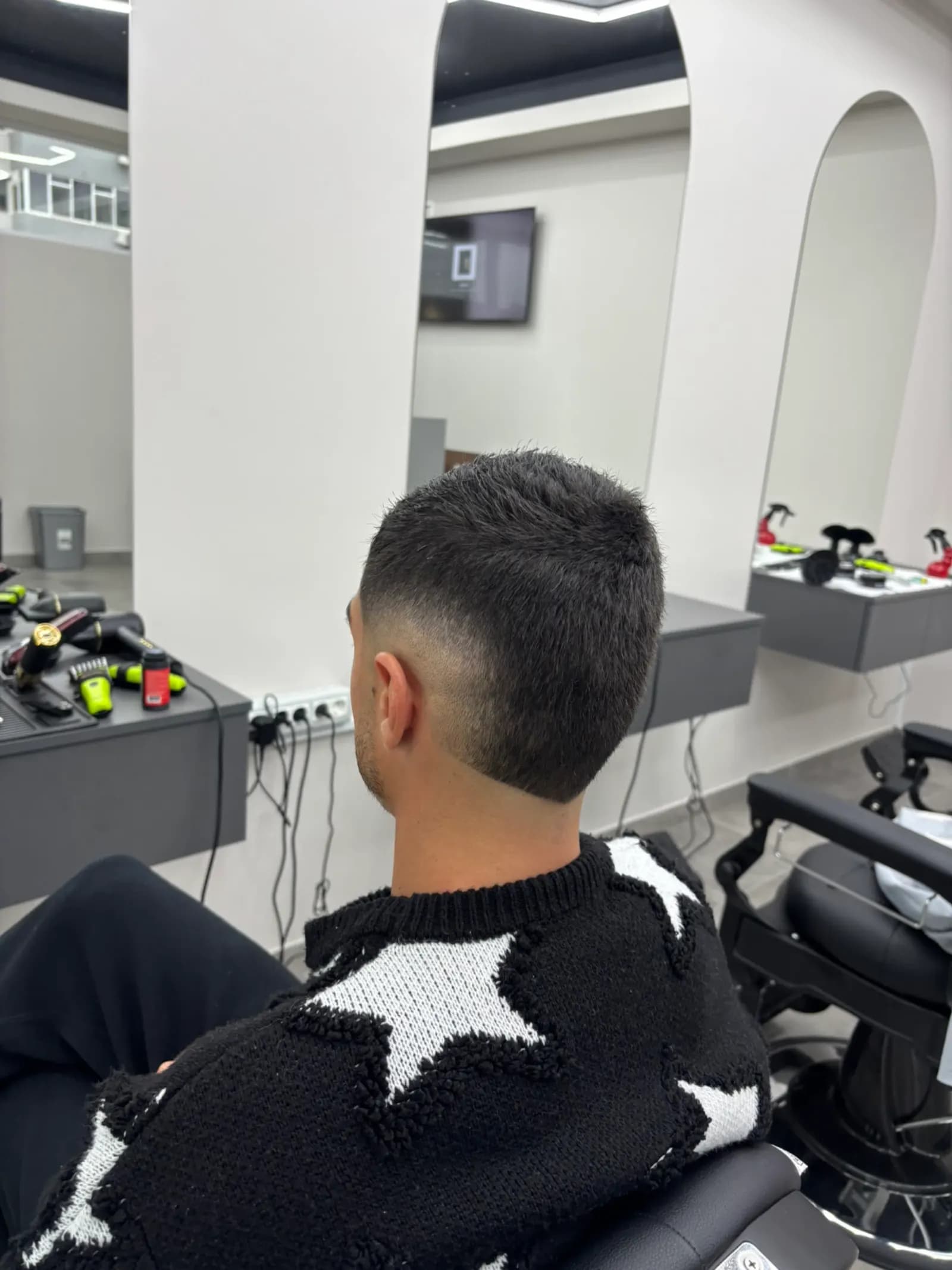 Crop fade proaspăt făcut, văzut din spate, cu oglinzile în arcadă ale salonului