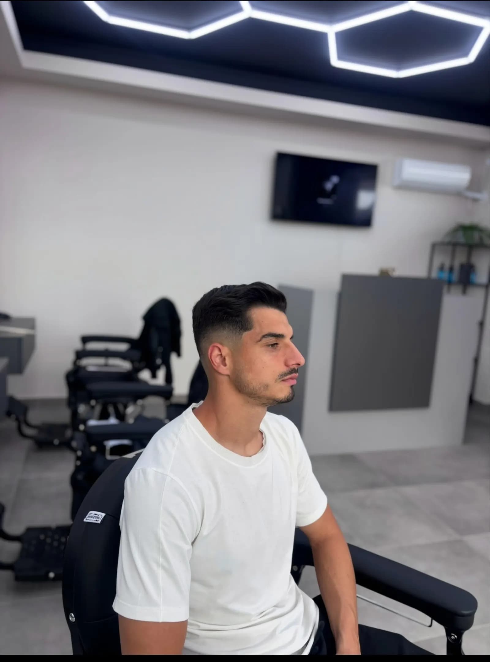 Fade proaspăt făcut la R|B Barbershop, cu tavanul în fagure în fundal